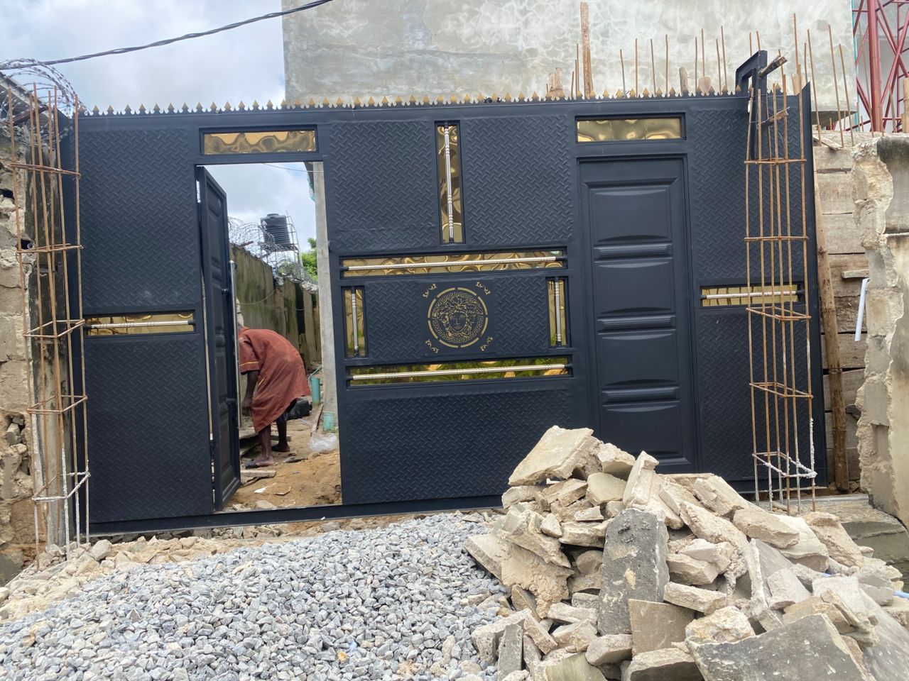 Matte black estate gate and perimeter wall with a lion crest detail